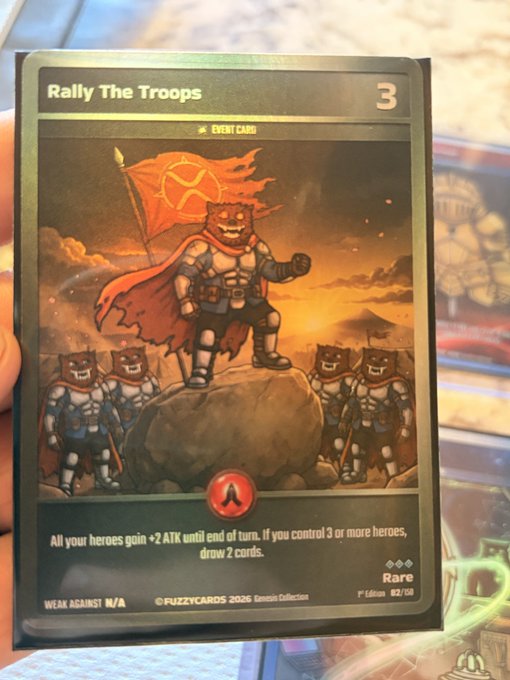 A trading card titled 'Rally The Troops' from the FuzzyCardz 2026 Gemini Collection, showing armored cat warriors with a red flag and text describing an attack buff ability.