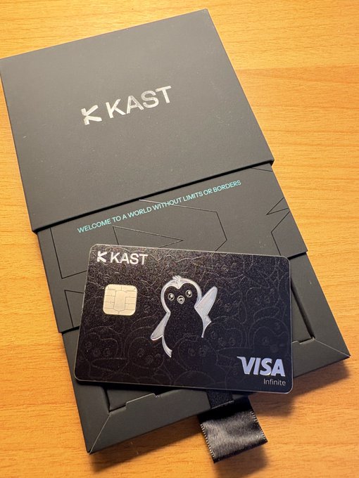A sleek black KAST Visa Infinite card featuring the iconic Pengu character rests on its branded packaging, which displays "WELCOME TO A WORLD WITHOUT LIMITS OR BORDERS," visually showcasing the new card highlighted in the post for its global spending capabilities and cashback rewards.