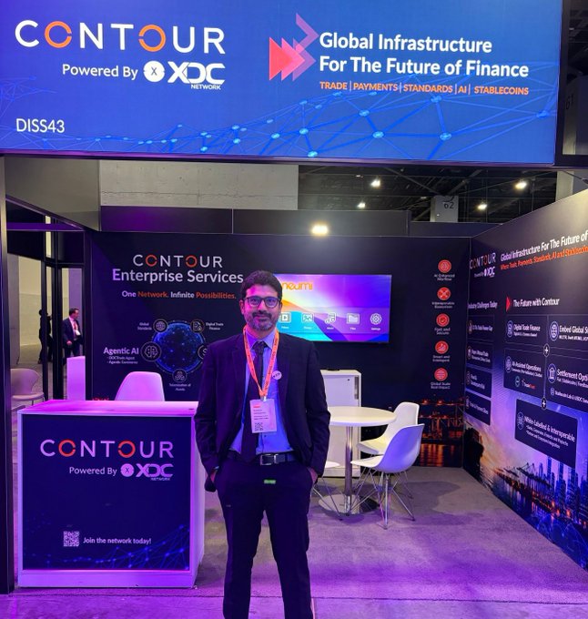 A man in a dark suit stands in front of a Contour Network exhibition booth at an industry event, with signage reading 'Global Infrastructure For The Future of Finance' and 'Powered By XDC Network'.