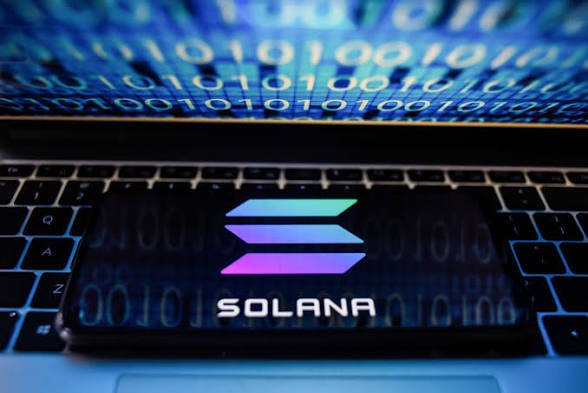 A smartphone displaying the Solana logo and text rests on a laptop keyboard, with glowing blue binary code (1s and 0s) projected in the background. The image visually reinforces the post's message of long-term faith in Solana, symbolizing the blockchain's digital foundation and its promise as the future of decentralized finance, even amid current bear market conditions.