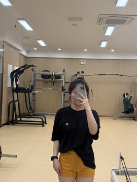 A person takes a mirror selfie in a gym while wearing a black shirt featuring the #Binance logo, capturing their fitness journey as they return to training after a break. The image reflects the post's message of dedication and perseverance, tying together physical strength-building with the crypto community.