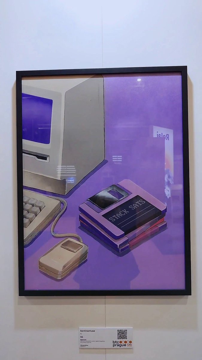 The image features an art piece that depicts a computer monitor, keyboard, and mouse placed together with a purple background. The artwork has a unique style reminiscent of the early days of computing when floppy disks were popular. The artist's signature can be seen in the bottom right corner of the painting. The post includes text such as "Just a glitch in the matrix. Keep stacking." and "@BTCPrague".