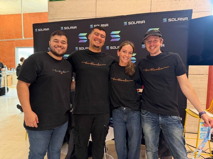Four people in matching black t-shirts pose in front of a Solana-branded backdrop at what appears to be a tech event.