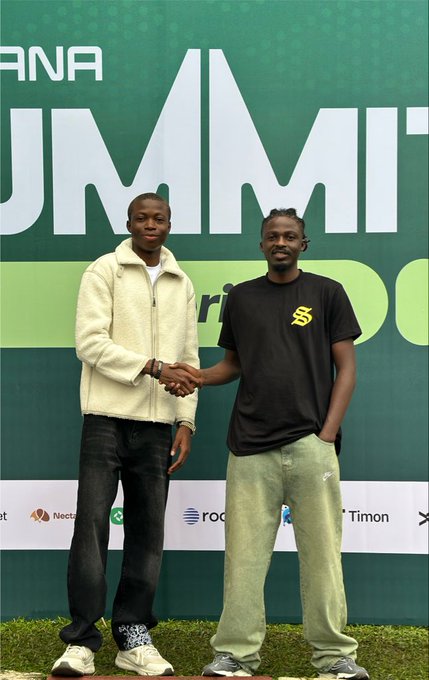 Two young men shaking hands in front of a green banner reading 'UMMI' with sponsor logos including Nectr, Rock, and Timon at the bottom.