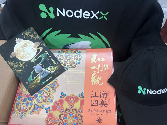 A Nodex-branded black bag, cap, and cards with Chinese text including 'Nodex' and '知味观江南四美' (Zhi Wei Guan Jiang Nan Si Mei) are displayed on a wooden surface.