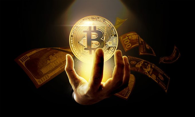 A stylized image shows a hand holding up a glowing golden Bitcoin coin, surrounded by floating gold and currency bills against a dark background.