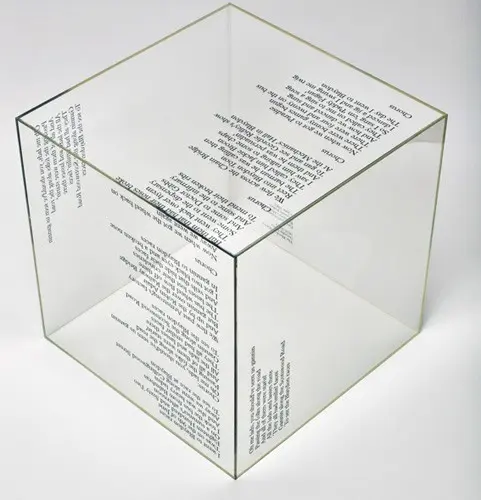 A transparent glass cube containing printed text from a book chapter, with the words visible through the walls of the cube.