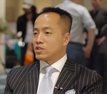 A man with short dark hair, wearing a pinstriped suit jacket, white dress shirt, and light gray tie, is captured mid-conversation in what appears to be an indoor social setting. The accompanying post identifies the individual as Harry Yeh, the Fantom blockchain backer and Quantum Fintech Group founder, who reportedly died after falling from a 30th-floor luxury apartment building in Asunción, Paraguay.