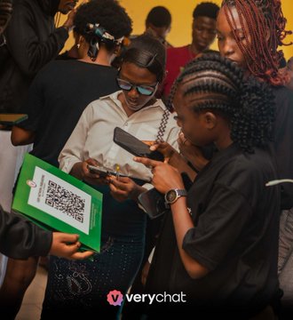 A young Nigerian university student promotes the Verychat app, featuring its QR code, to peers at a campus event, with the "verychat" logo and "$VERY" branding visible. The image aligns with the post's celebration of Verychat's growth from its early buggy app days to becoming a major ecosystem within the university community.