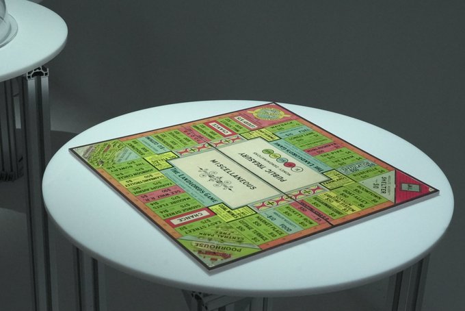 A folded Monopoly board placed on a round white table, showing the board sections for Reading Railroad, Water Works, and Pennsylvania Avenue.