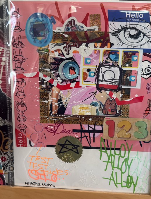 A mixed-media collage artwork featuring a Tamagotchi device, anime eyes, and various stickers on a pink background, with visible text including "Hello my name is," "123," and "Aphrodite Alloy," tied to a giveaway promotion for the Aphrodite Alloy NFT collection.