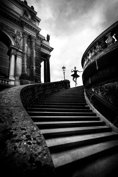 The image features a staircase with a woman dancing at the top of the stairs, dressed in a ballerina costume. The photo has been edited to make her appear as if she's floating or dancing on air. The caption below the image reads "✧ Stairway to Heaven ✧ by @gulyildizart SOLD↴ to @uncleshalin for 0.38 ETH ($621.90) $RARE".
