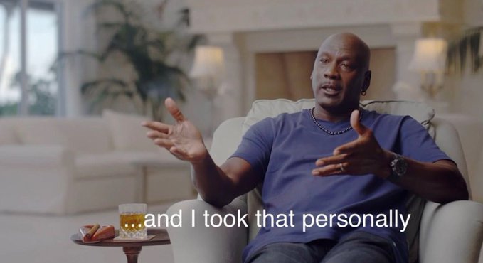 Michael Jordan sits in a cream-colored chair, gesturing with his hands while speaking, with the subtitle 'and I took that personally' displayed at the bottom.