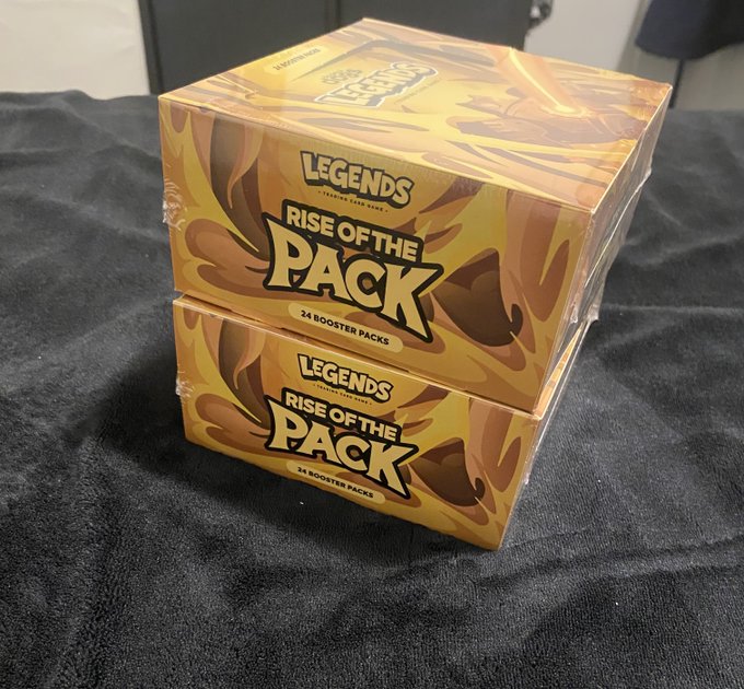 Two sealed 'Legends Rise of the Pack' booster boxes, each containing 24 packs, are stacked on a black cloth surface.