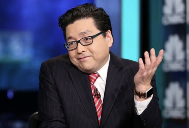 An Asian man in a dark pinstripe suit, red striped tie, and glasses gestures while speaking in a TV studio setting. The image does not directly relate to the post about Tom Lee's BitMine purchasing ETH, though the man pictured resembles financial commentator Tom Lee.