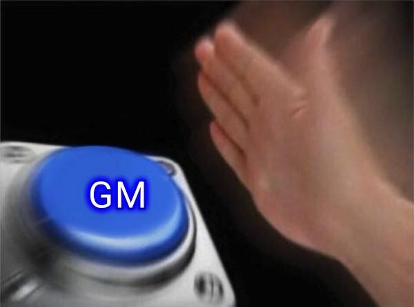 A hand reaching toward a large blue button labeled 'GM' on a metallic surface against a black background.