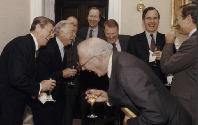 Historical photo of a group of smiling men in suits drinking champagne together, appearing to celebrate.