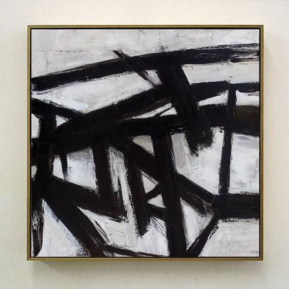 A square abstract painting hangs on a light-colored wall, featuring thick black gestural brushstrokes over a white and pale gray background.