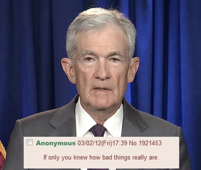 Fed Chair Jerome Powell stands at a podium against a blue curtain during a press briefing, while an anonymous comment dated 03/02/12 (Fri) 17:39, No. 1921453 reads "If only you knew how bad things really are." The image underscores concerns that today's 25bps Fed rate hike may not fully reflect underlying economic strains.