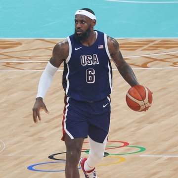 LeBron James, wearing his Team USA jersey with the number 6, dribbles the ball during what appears to be an Olympic basketball game. The image contrasts with the post's news about his lucrative $15M endorsement deal with Polymarket, which reportedly exceeds his $4M NBA salary with the Philadelphia 76ers.