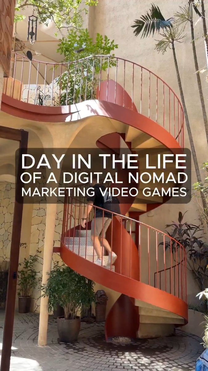 urns of plants sit on a balcony, with a person ascending the red spiral staircase and text reading "Day in the Life of a Digital Nomad" above it.