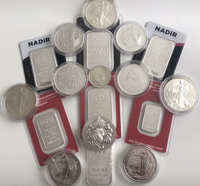 A collection of "NADIR" refined silver bars and bullion coins featuring American Silver Eagle and Britannia designs, displayed in their original packaging and marked with "ONE OZ FINE SILVER" and ".999" hallmarks—perfectly capturing the "Silver Is Key" message for a Stacking Sunday post showcasing precious metal stacking.