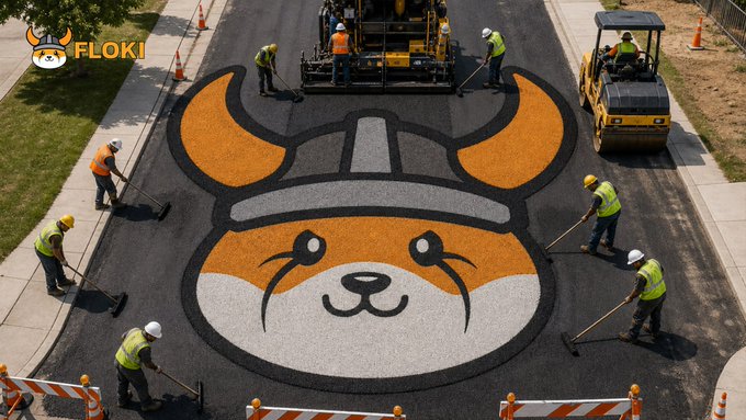 A "FLOKI" logo watermark sits in the top left of an image showing a construction crew in high-visibility vests using rollers and heavy machinery to pave asphalt in the shape of the Floki Viking dog mascot, literally manifesting the "New Viking road is done boss" message by turning a street into a giant Floki emblem.
