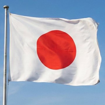 The national flag of Japan, featuring a red circle on a white background, waving against a clear blue sky.