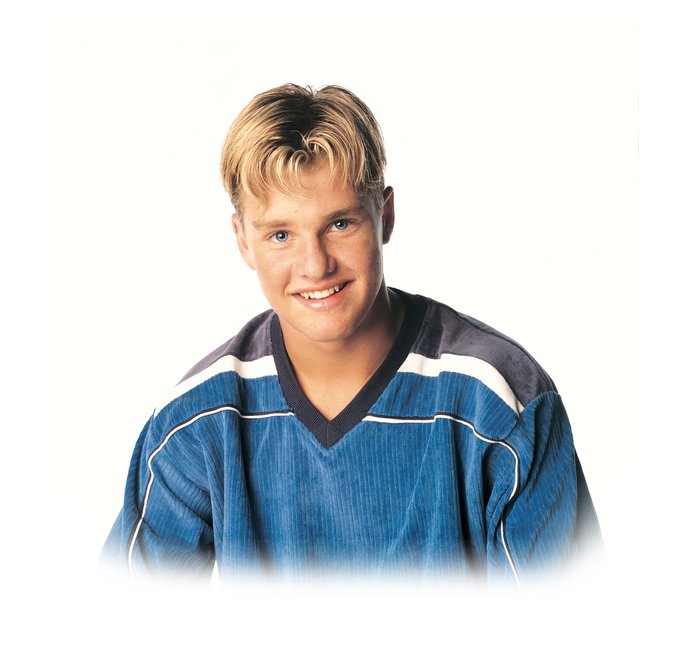 A studio portrait of a smiling young man with blonde hair wearing a blue athletic jersey.