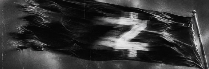 A tattered black flag with a white 'Z' symbol, appearing to flutter in the wind in a black and white image.