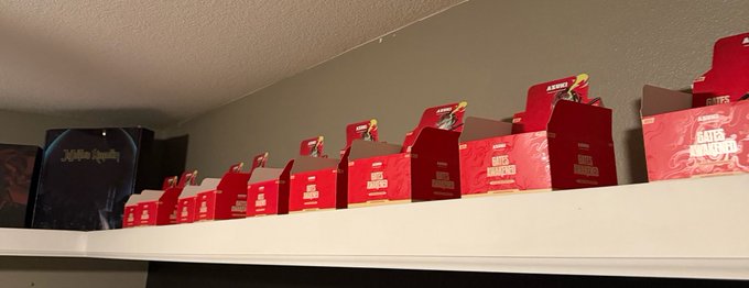 A shelf lined with red "Brawl Stars" merchandise boxes alongside a black "Mythic Loyalty" box, indicating the poster's interest in trading or purchasing Shaolin Showdown and Zero Prism Brawl Stars items. The arrangement of multiple identical red boxes suggests the poster may be a collector seeking these specific Brawl Stars figures or skins.