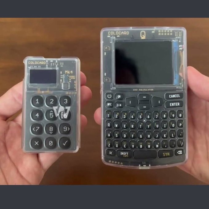 Two hands hold transparent electronic devices branded 'COLDCARD' against a wooden surface — a small Mk4 numeric keypad device on the left and a larger Q model with a full QWERTY keyboard on the right.