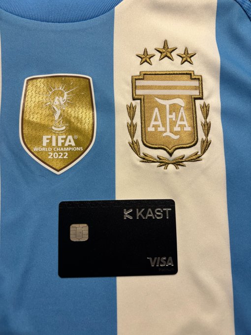 A light blue and white striped Argentina national football jersey features the FIFA World Champions 2022 patch and AFA crest, with a black 'K KAST' Visa Platinum card placed on top.
