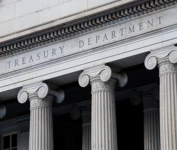The stone facade of a building displays large fluted columns beneath an inscription that reads 'TREASURY DEPARTMENT'.