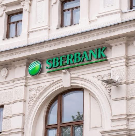 The exterior of a classical-style building featuring an ornate archway and green 'SBERBANK' signage with the bank's logo.