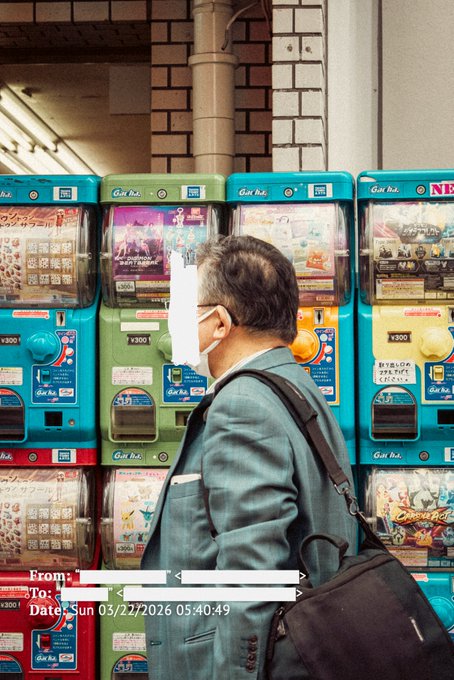 An older man wearing a gray suit jacket, white mask, and black shoulder bag stands in front of a row of colorful Japanese capsule toy (Gacha) vending machines labeled ¥300, with overlaid text showing 'From:', 'To:', and 'Date: Sun 03/22/2026 05:40:49'.