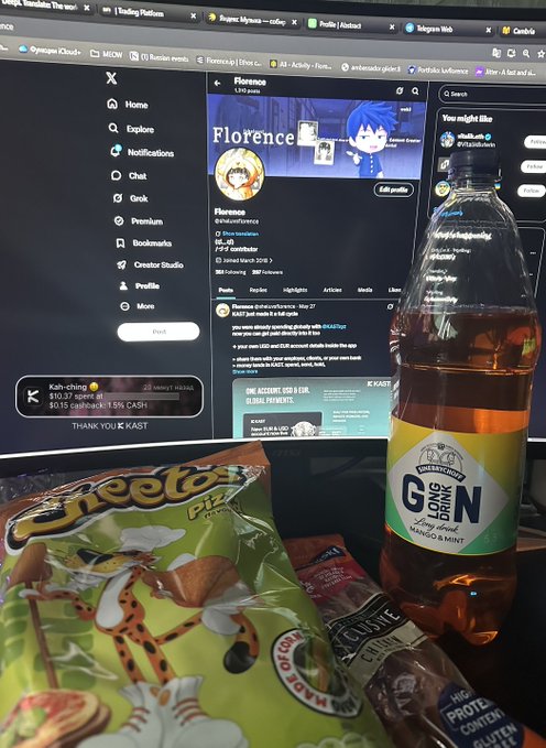 The image shows a snack box filled with Cheetos and a bottle of gin. There is also a bottle placed nearby. Additionally, there is a computer screen visible behind the snacks, featuring an interactive website or Twitter account that reads "Florence". The overall scene suggests a casual setting where someone has enjoyed a snack while using their computer to interact with the online platform.
