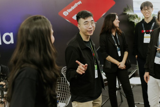Attendees converse at the RedotPay booth, with the company's logo prominently displayed on the backdrop, reflecting the brand's active presence and community engagement at Blockchain Rio in Brazil.