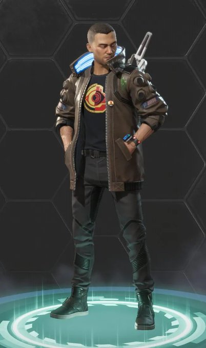 A male character named "Crypto" from Apex Legends stands confidently in his signature cyberpunk-style skin featuring a brown bomber jacket, dark pants, and a glowing blue device on his shoulder, reimagined for the Cyberpunk 2077 crossover. The Apex Legend icon on his shirt confirms his identity as Crypto from Apex Legends.