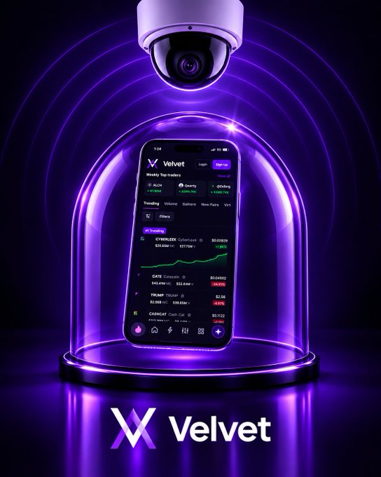 A smartphone displaying the Velvet trading app, showing a "Weekly Top Traders" leaderboard with token tickers like $ALCH, $Gravity, and $Orderly alongside real-time price charts and market data, is enclosed under a protective glass dome beneath a watchful security camera—visually reinforcing the caption's "Your trades. Protected. Always watching." message. The glowing purple aesthetic and the bold "Velvet" branding below tie the imagery to the pitch of a secure, real-time trading terminal for fast-moving crypto traders.