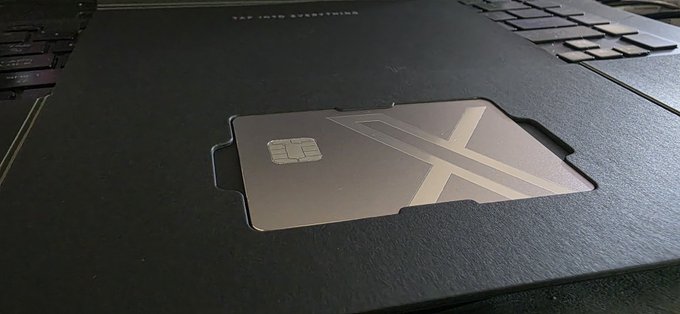 A metallic cold wallet card with an embedded chip and large 'X' design resting in a black cutout holder on a laptop, with text reading 'TAP INTO EVERYTHING'.
