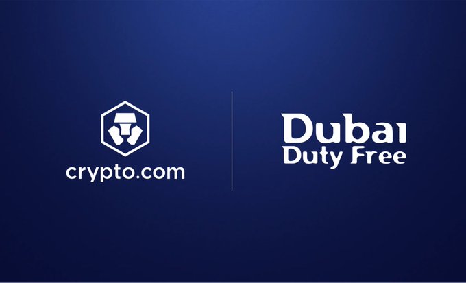 A dark blue graphic displays the white crypto.com logo on the left and 'Dubai Duty Free' text on the right, separated by a vertical line.
