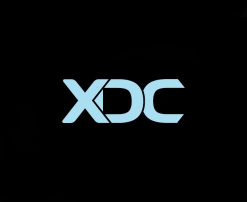 The image displays the light blue "XDC" logo on a black background, representing the cryptocurrency that has achieved new milestones in tokenized real-world assets and enabled native on-chain staking.