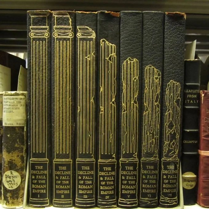A row of seven black hardcover books titled 'THE DECLINE & FALL OF THE ROMAN EMPIRE' (Volumes I through VII) stand on a shelf, each spine featuring an illustration of a ruined classical column.