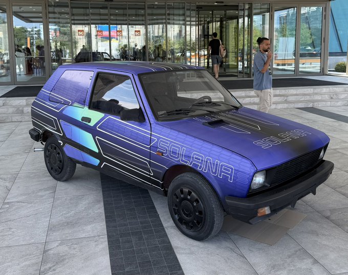 A vintage hatchback is wrapped in a Solana-themed blue and purple design featuring circuit-like graphics and the word "SOLANA" along the side, matching the crypto enthusiasm for Solana Summit Serbia.