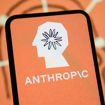 A close-up of a smartphone displaying the Anthropic logo, which features a white silhouette of a human head profile containing a flower/starburst design, with the word 'ANTHROPIC' below it on an orange background.