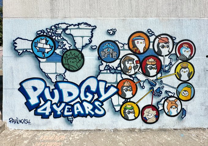 A colorful street mural on a wall featuring a world map, cartoon characters in circles, and large text reading 'PUDGY 4 YEARS' with 'PAUL&NOISH' signature.