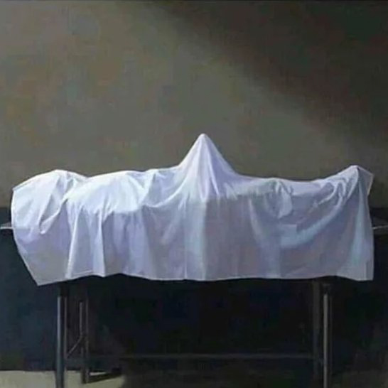 A real white sheet draped over an unseen object on a table, resembling a minimalist ghost sculpture in a dimly lit room.