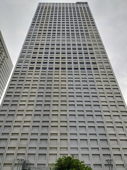 A tall, gray high-rise building photographed from a low angle against an overcast sky.