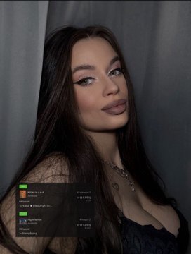 A portrait of a young woman with long dark hair and makeup, with a small dark Spotify playlist overlay visible in the lower left corner.
